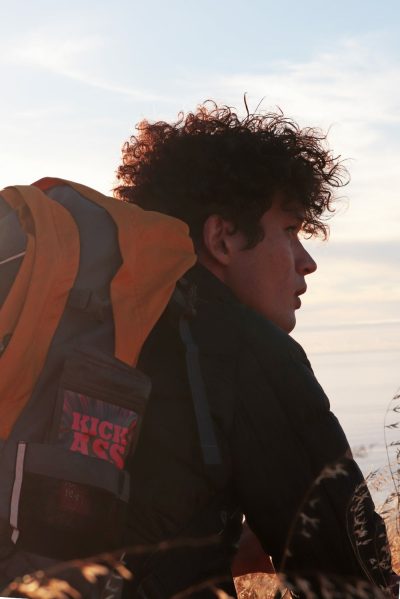 Athlete with orange backpack with Kick Ass whey protein pack in bag.